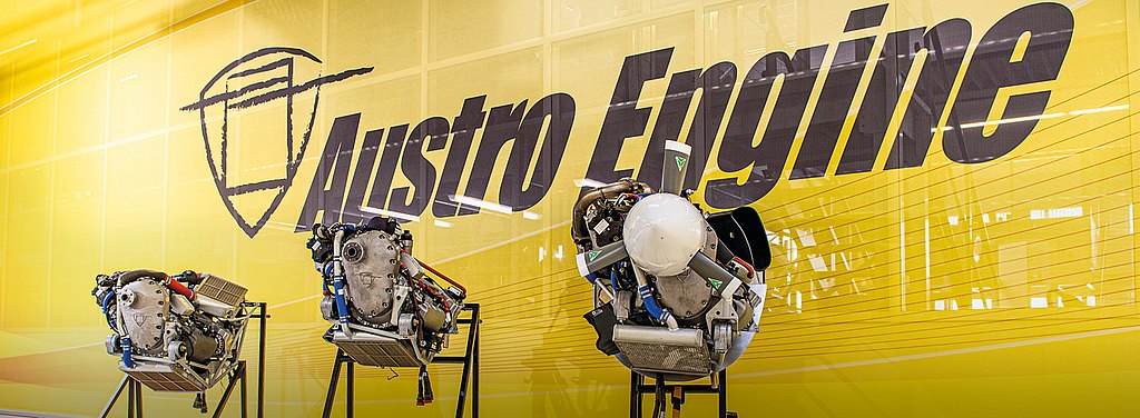 Engines displayed in front of Austro Engine logo wall. 